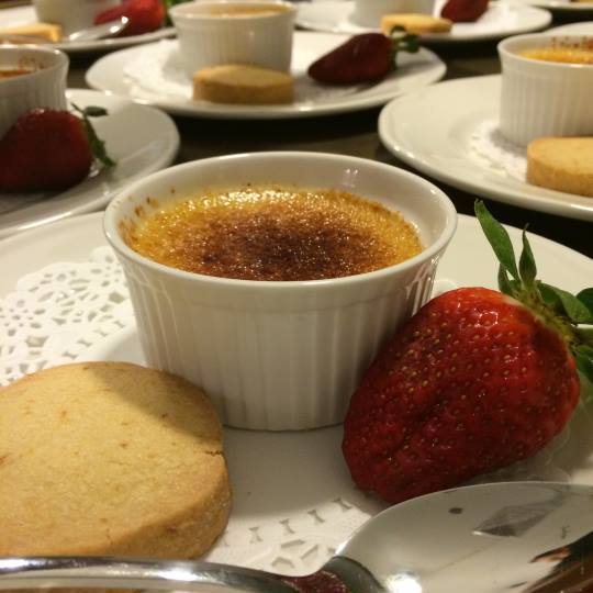 close up of small dishes of crème brulée plates with strawberries and biscuits